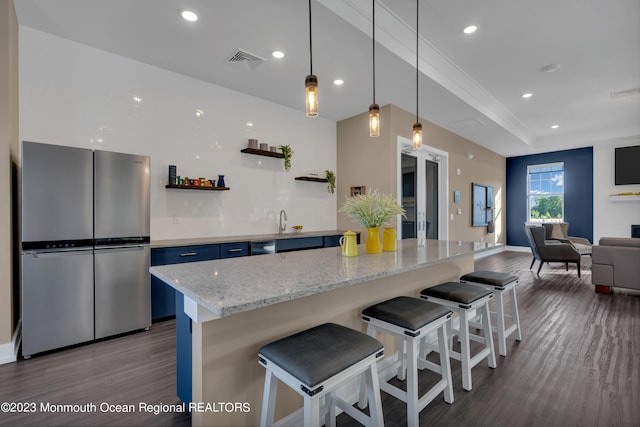 kitchen featuring a breakfast bar, freestanding refrigerator, visible vents, and open shelves