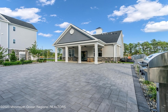 rear view of house featuring ceiling fan and stone siding