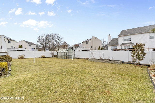 view of yard with a fenced backyard, a residential view, an outdoor structure, and an exterior structure