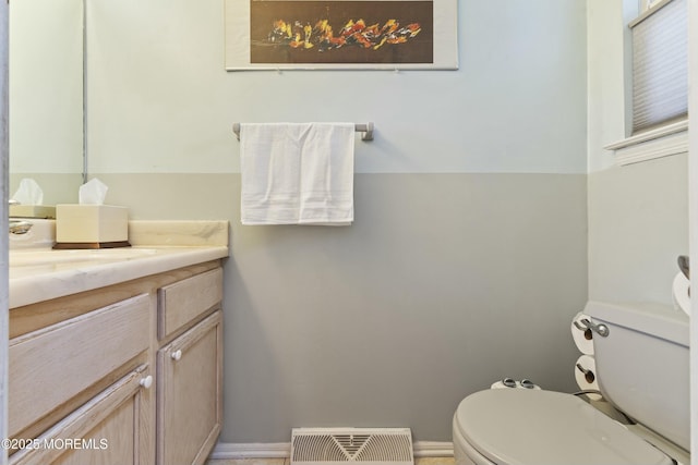 half bathroom with toilet, baseboards, visible vents, and vanity