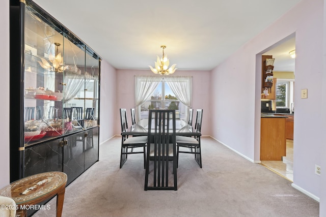 dining room with light carpet, baseboards, and an inviting chandelier