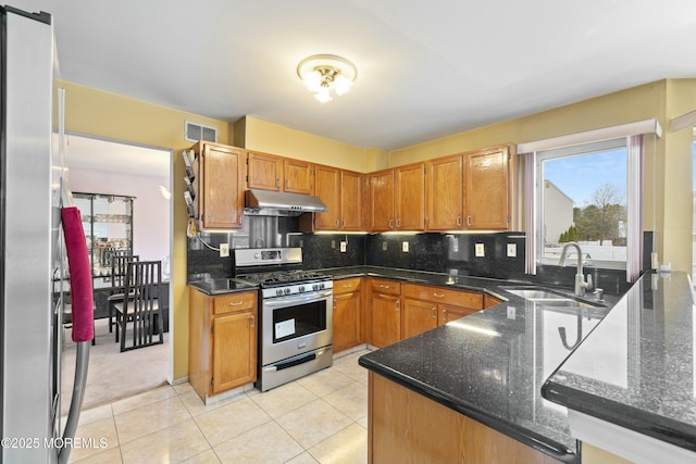 kitchen with backsplash, gas stove, a sink, and under cabinet range hood