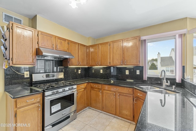 kitchen featuring under cabinet range hood, a sink, visible vents, backsplash, and gas range