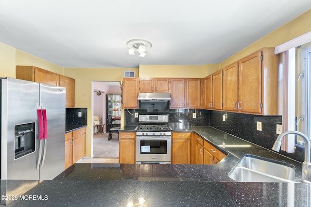 kitchen featuring under cabinet range hood, stainless steel appliances, a sink, visible vents, and backsplash