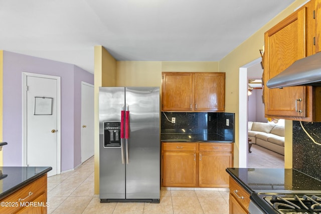 kitchen featuring brown cabinets, stainless steel fridge, backsplash, and light tile patterned floors