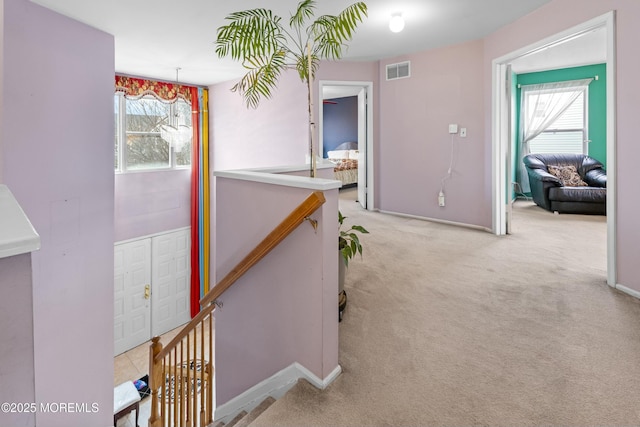 corridor featuring visible vents, carpet flooring, and an upstairs landing