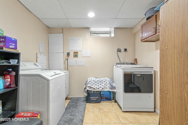 washroom with light tile patterned floors, washing machine and dryer, cabinet space, and baseboards