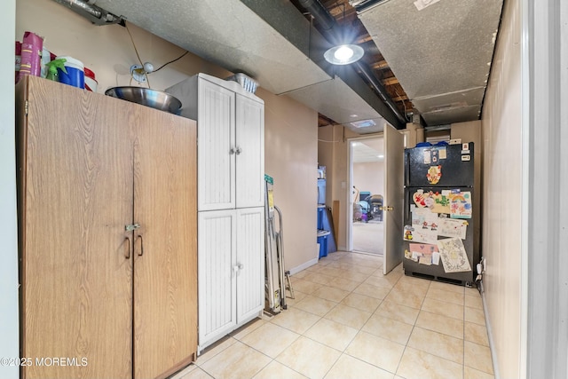 interior space featuring light tile patterned floors, a textured ceiling, and freestanding refrigerator