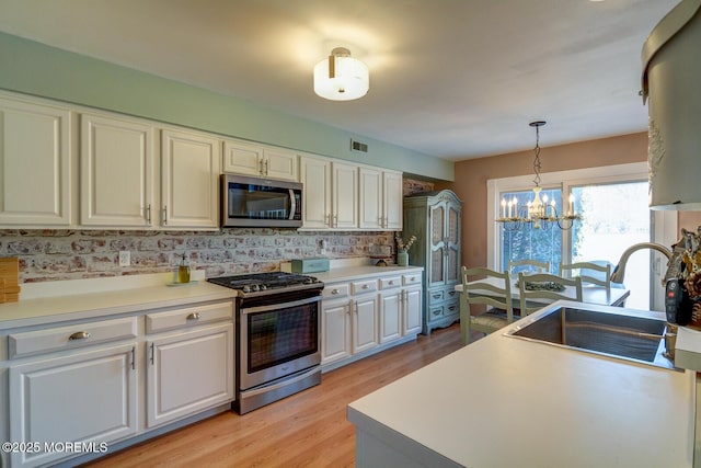 kitchen featuring a sink, white cabinets, visible vents, and stainless steel appliances