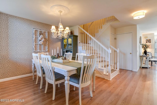 dining room with baseboards, wallpapered walls, stairs, and light wood-style floors