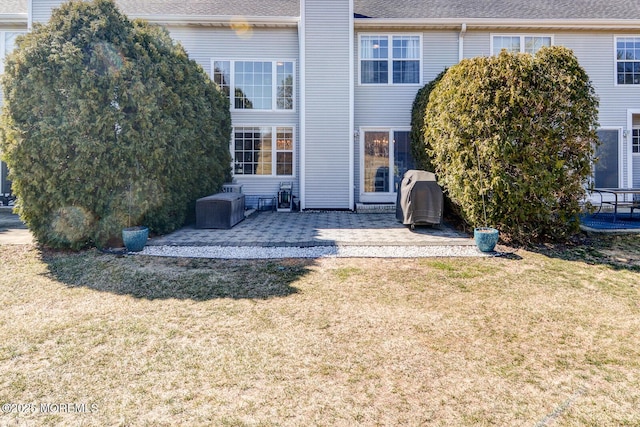 back of property featuring a shingled roof, a yard, a patio area, and a chimney