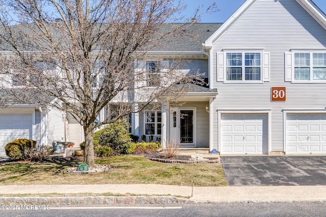 multi unit property with aphalt driveway, an attached garage, and roof with shingles