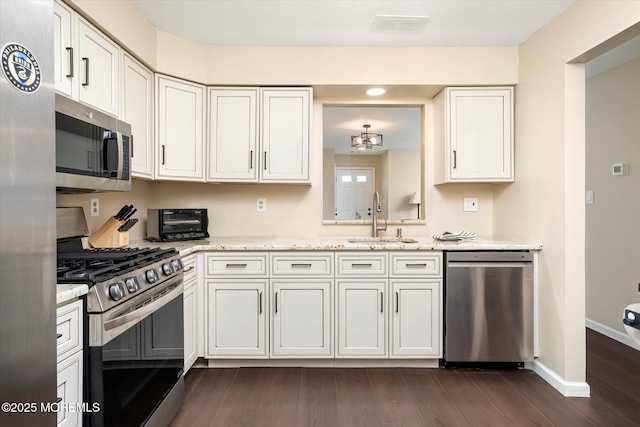 kitchen featuring dark wood-style flooring, stainless steel appliances, visible vents, a sink, and light stone countertops