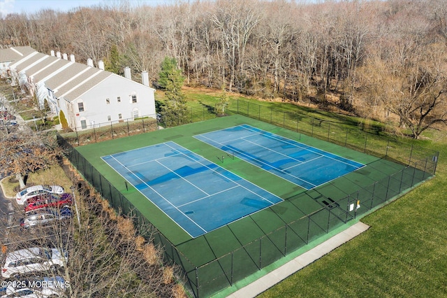 view of tennis court with a lawn and fence