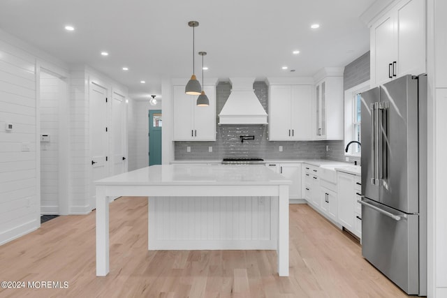 kitchen featuring appliances with stainless steel finishes, a center island, custom range hood, and a sink