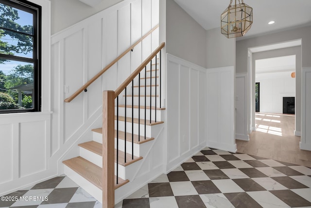 121 Black Point Rd, Rumson, NJ 07760 - stairs with a decorative wall, a chandelier, recessed lighting, wainscoting, and a glass covered fireplace