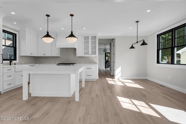 121 Black Point Rd, Rumson, NJ 07760 - kitchen featuring custom range hood, light countertops, white cabinetry, glass insert cabinets, and light wood-style flooring