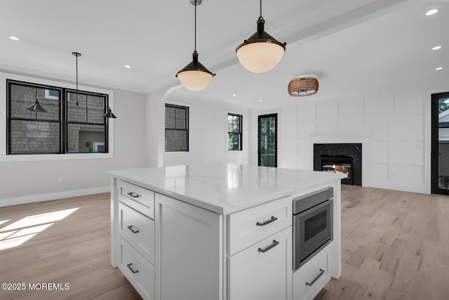 121 Black Point Rd, Rumson, NJ 07760 - kitchen with stainless steel microwave, light wood-style flooring, a high end fireplace, white cabinets, and hanging light fixtures