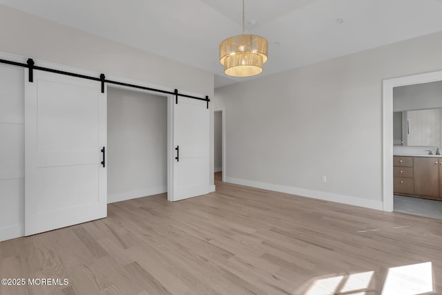 121 Black Point Rd, Rumson, NJ 07760 - unfurnished bedroom with a barn door, light wood-style floors, and connected bathroom