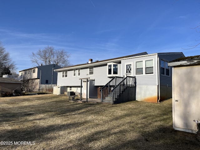 rear view of house featuring fence, central AC unit, and a yard