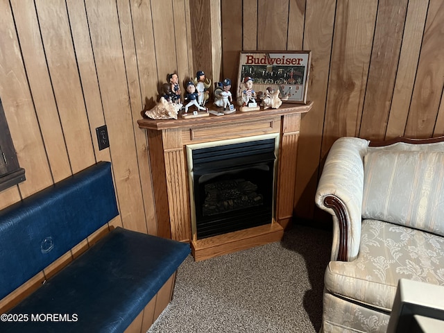 living area with carpet, a fireplace with raised hearth, and wooden walls