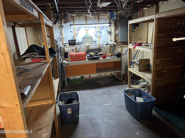 interior space featuring electric panel, unfinished concrete flooring, and a workshop area