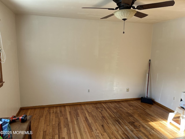 empty room featuring a ceiling fan, baseboards, and wood finished floors