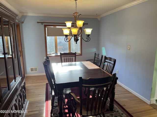 dining room with light wood-type flooring, visible vents, a notable chandelier, and ornamental molding