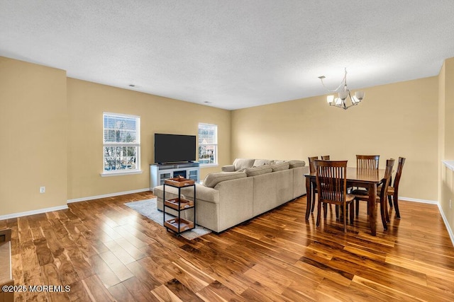 living room featuring a chandelier, a textured ceiling, wood finished floors, and baseboards