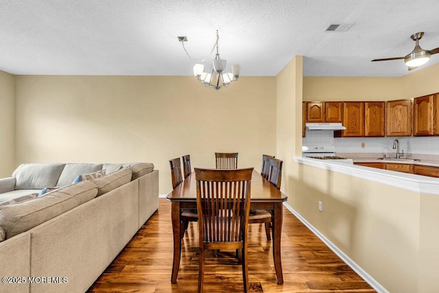 dining area featuring light wood finished floors, baseboards, visible vents, and ceiling fan with notable chandelier