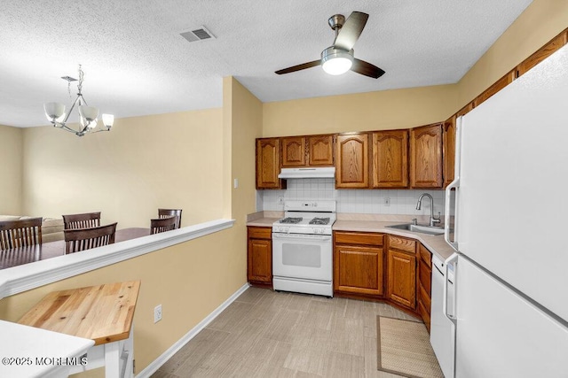 kitchen featuring white appliances, light countertops, hanging light fixtures, and under cabinet range hood