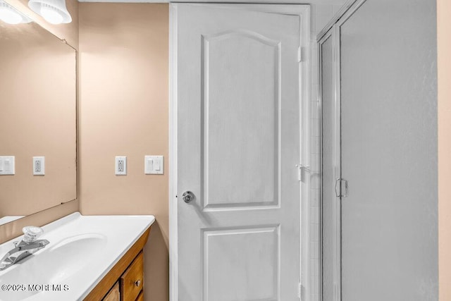 bathroom featuring a shower with door and vanity