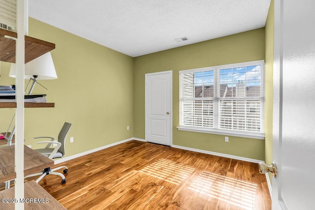 office area with visible vents, a textured ceiling, baseboards, and wood finished floors