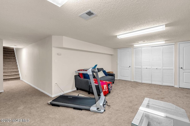 workout room with carpet floors, visible vents, and a textured ceiling