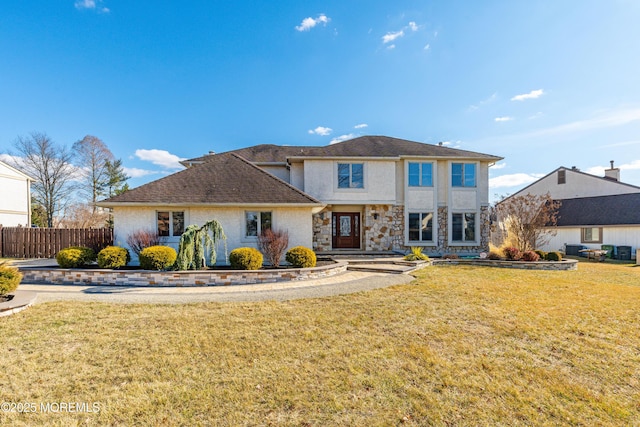 traditional-style home with stucco siding, stone siding, fence, and a front yard