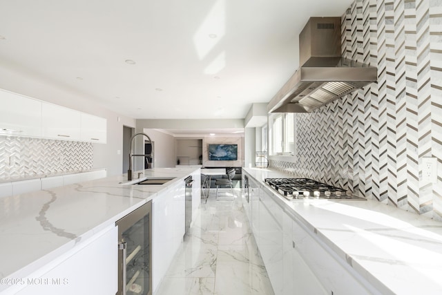 kitchen with beverage cooler, stainless steel appliances, a sink, wall chimney exhaust hood, and modern cabinets