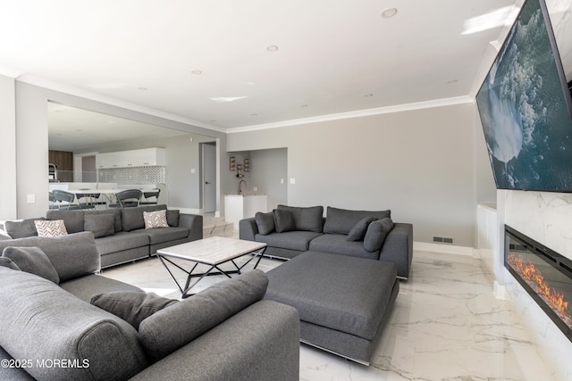 living room with a glass covered fireplace, marble finish floor, visible vents, and crown molding