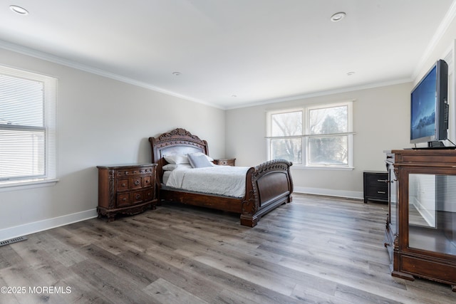 bedroom with visible vents, crown molding, baseboards, and wood finished floors