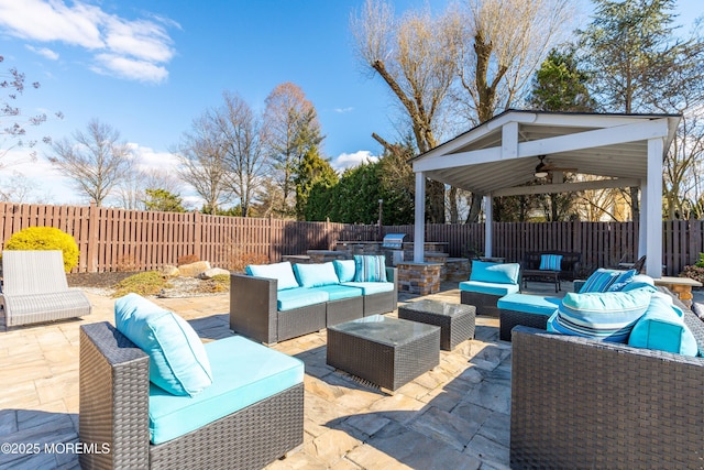 view of patio / terrace with an outdoor hangout area, exterior kitchen, a fenced backyard, and a ceiling fan