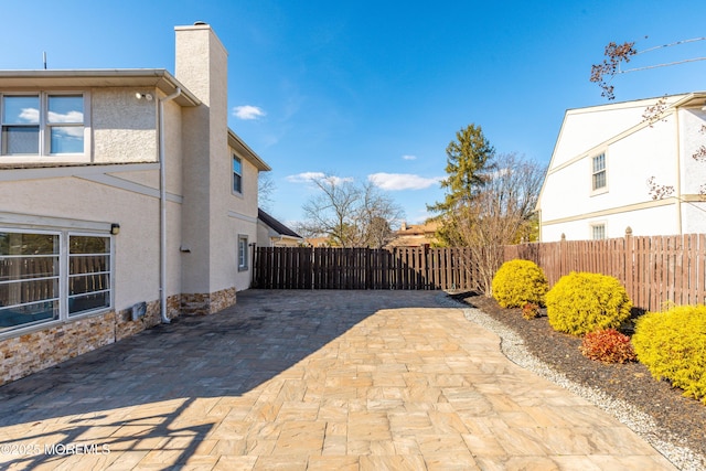 view of property exterior with a chimney, a patio area, fence, and stucco siding