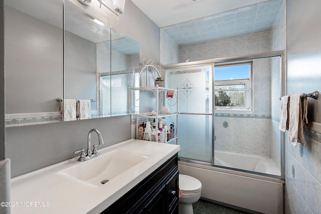 bathroom featuring enclosed tub / shower combo, vanity, and toilet