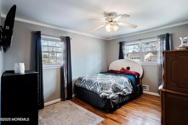 bedroom featuring ornamental molding, multiple windows, visible vents, and light wood-style floors