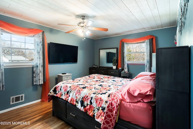 bedroom featuring a ceiling fan, visible vents, baseboards, and wood finished floors