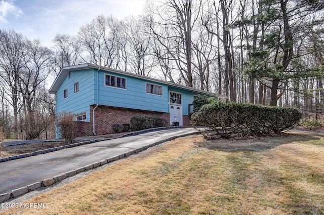 raised ranch featuring a front yard, brick siding, and driveway