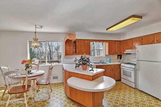 kitchen featuring brown cabinets, white appliances, and light countertops