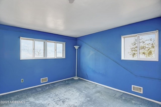 unfurnished room featuring visible vents, plenty of natural light, and carpet flooring