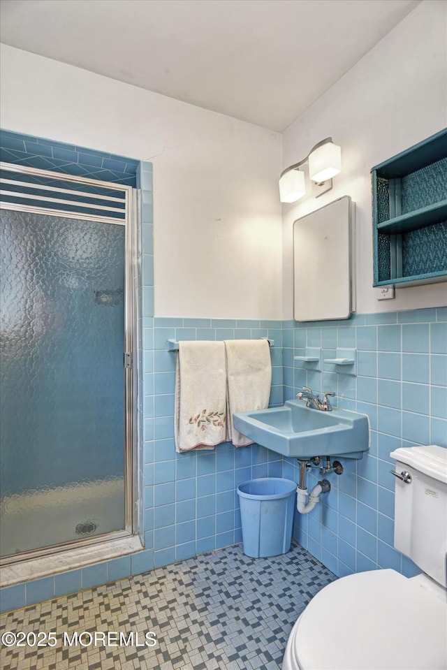 bathroom with tile patterned flooring, a shower stall, wainscoting, tile walls, and toilet