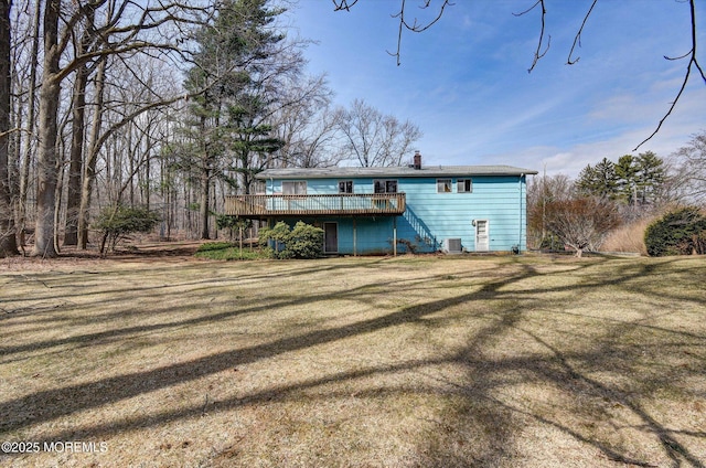 back of property with a wooden deck, central air condition unit, a lawn, and a chimney