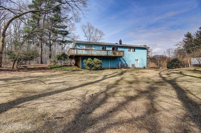 rear view of house featuring a deck, a lawn, and a chimney