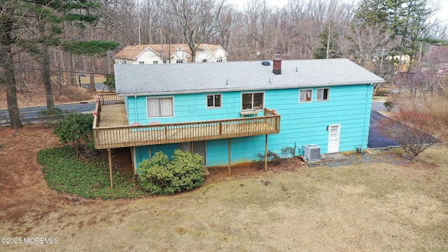 rear view of property featuring a wooden deck, central air condition unit, a chimney, and a yard